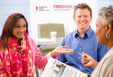 an image of 3 adults, 2 females and 1 male, standing around and chatting about medical stuff