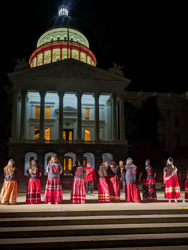 Girls in red ribbon skirts in front of the State Capitol.